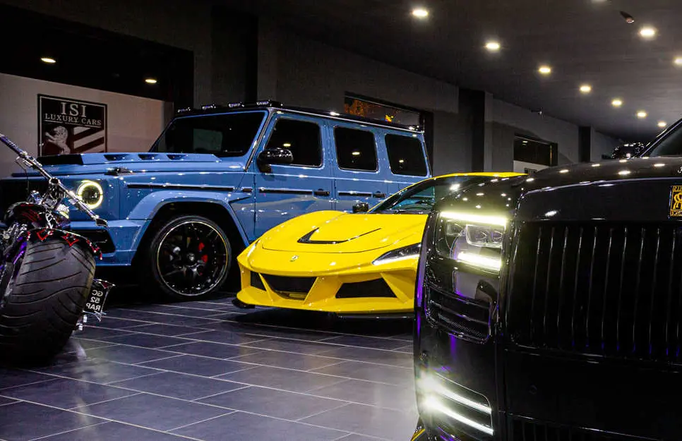 Light blue Mercedes G-Class next to other vehicles under the ISI wall crest