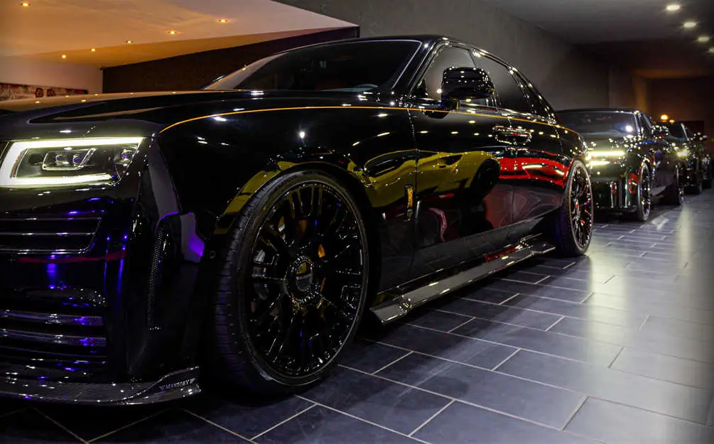 Black Rolls-Royce in profile, more vehicles from the lineup behind it
