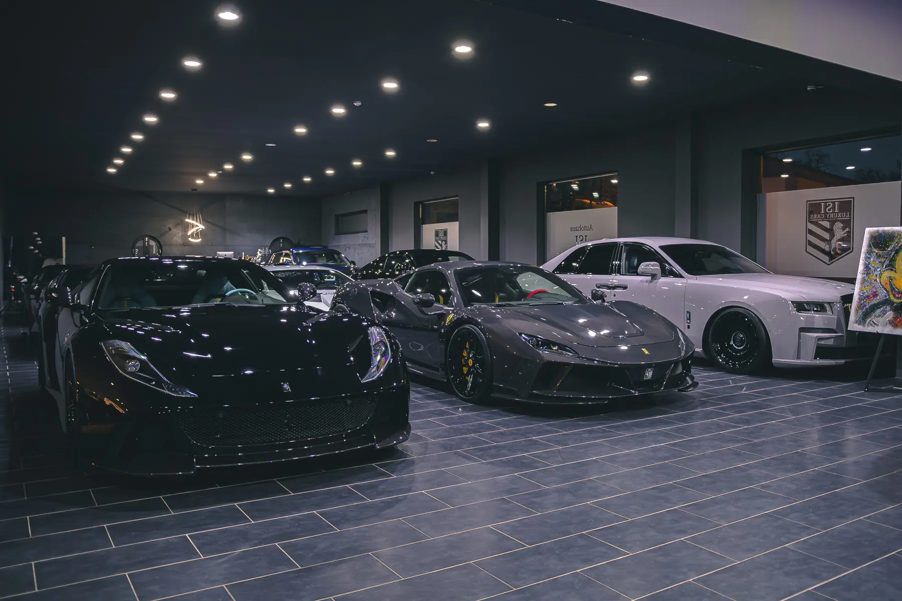 Wide view into the Autohaus ISI showroom hall with several sports cars and a Rolls-Royce